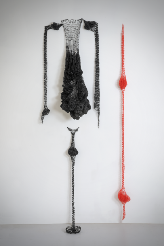 Foto einer Installation mit drei Objekten mit lockeren Maschen in Schwarz und Rot.